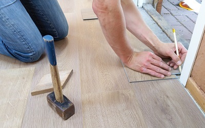 Person kneeling, measuring out floor