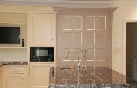 A light kitchen including a wall mounted microwave, and an island containing a sink.